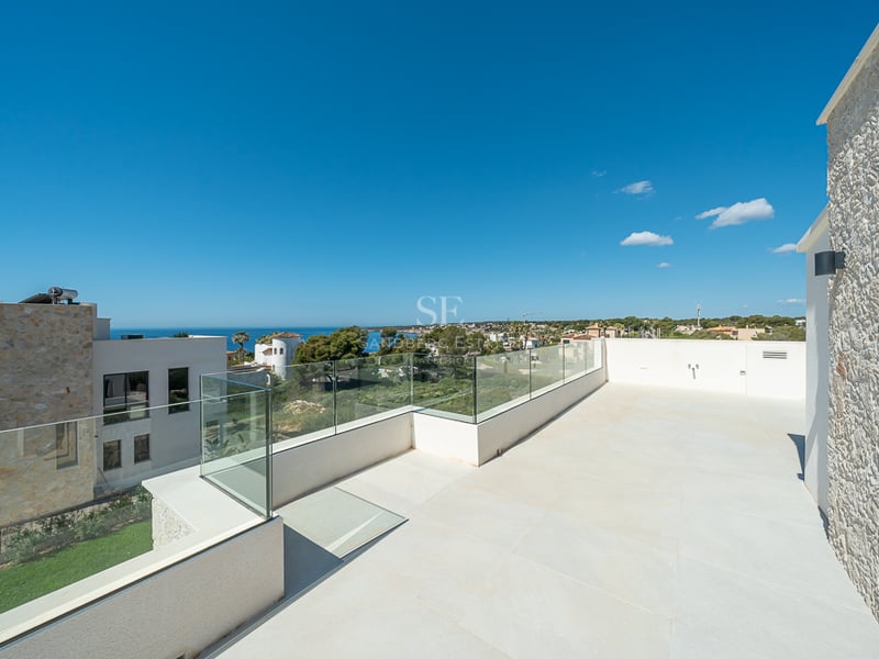 Grande terrasse moderne avec garde-corps en verre, sol en pierre claire et vue imprenable sur la mer Méditerranée.