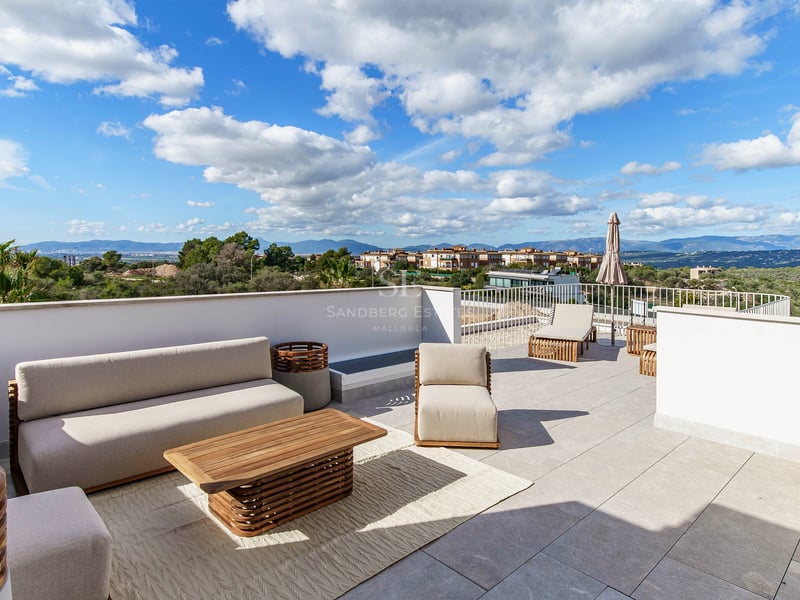 Terrasse moderne sur le toit avec canapés beiges, meubles en teck et vue sur les collines et les montagnes.