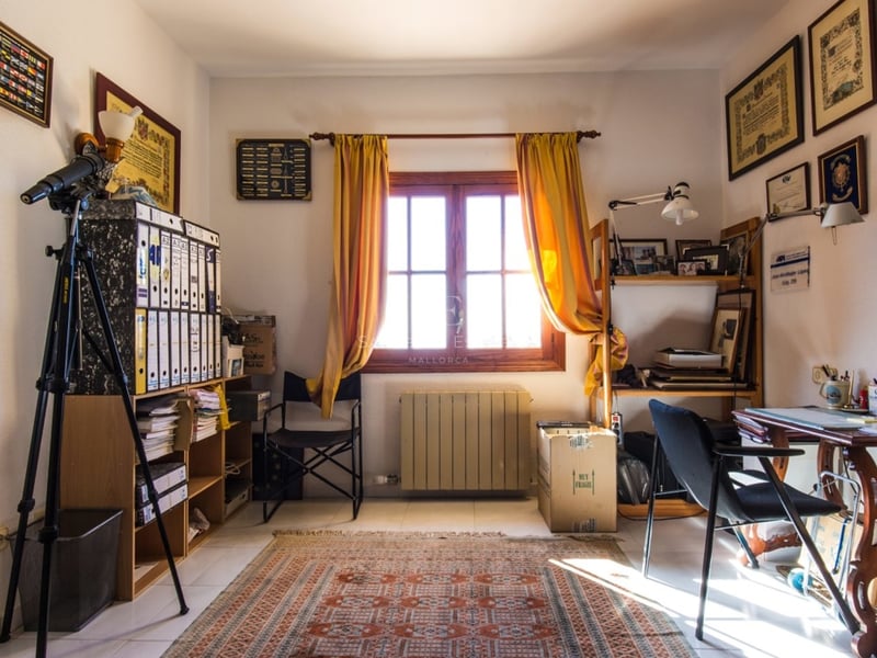 Bureau avec bureau en bois, télescope, étagères, rideaux jaunes et diplômes aux murs.