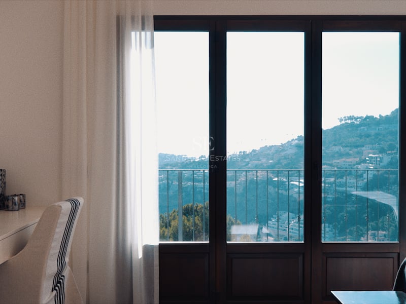 Chambre moderne avec bureau, TV murale et baies vitrées donnant sur une vue panoramique de la colline et de la mer.