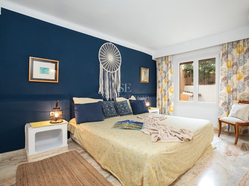 Chambre avec un grand lit, un mur d'accent bleu marine avec un attrape-rêve et un sol en marbre poli.