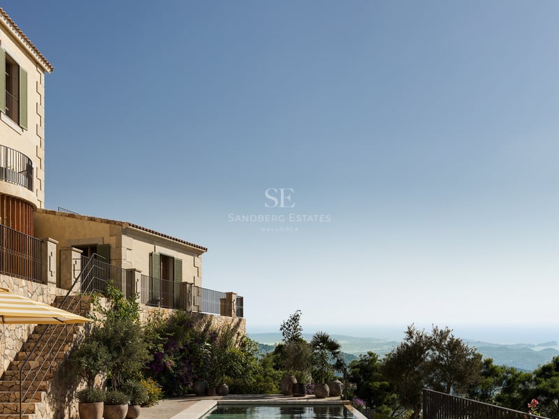 Piscine à débordement sur une terrasse en pierre naturelle avec bains de soleil et vue imprenable sur la côte.