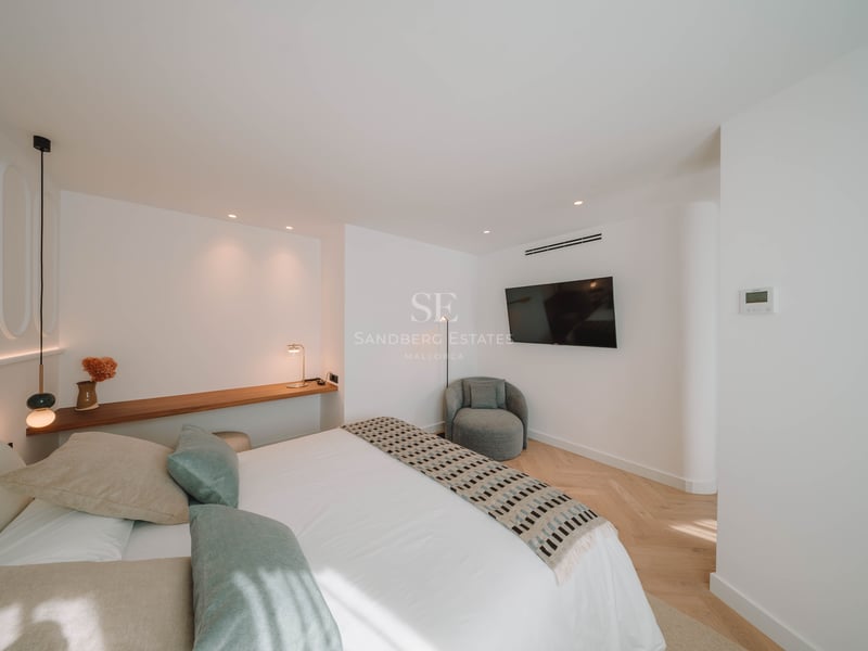 Chambre moderne avec lit blanc, coussins vert sauge, étagère en bois et parquet en chevrons.
