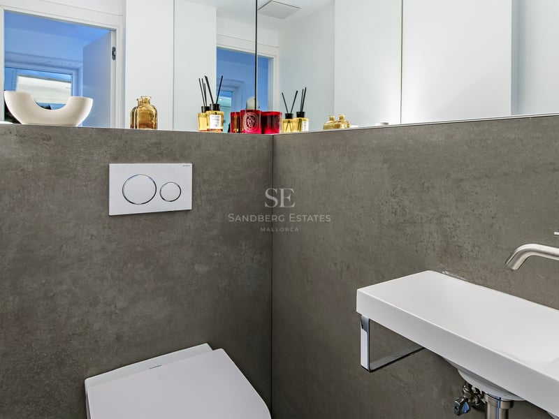 Salle d'eau minimaliste avec murs en grès cérame gris, lavabo suspendu blanc et grand miroir.