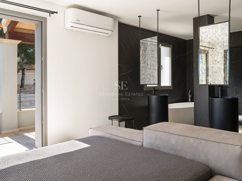 Chambre de luxe avec salle de bain ouverte en marbre noir, doubles vasques colonnes et accès terrasse.