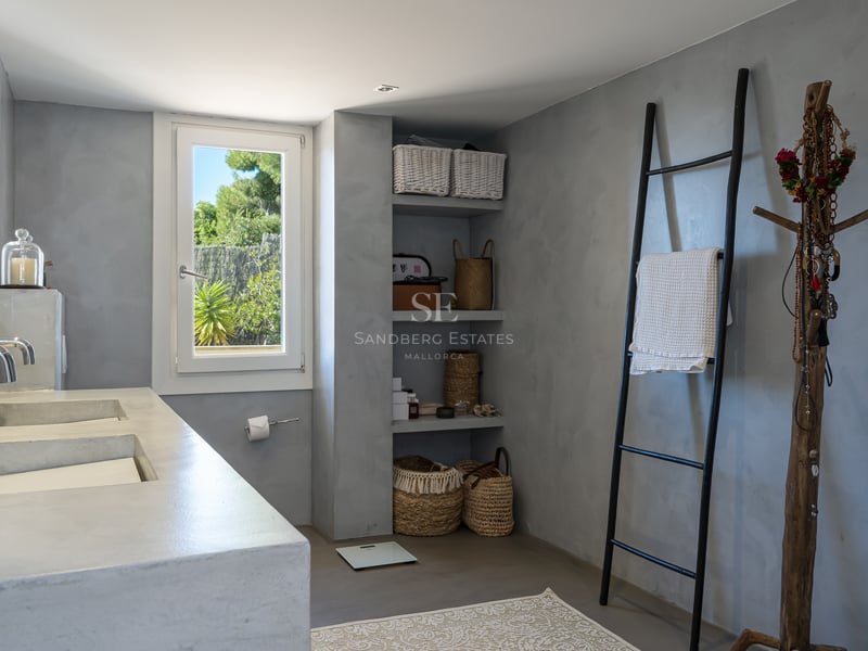 Salle de bain moderne avec double vasque en microciment gris, étagères ouvertes et échelle porte-serviettes noire.