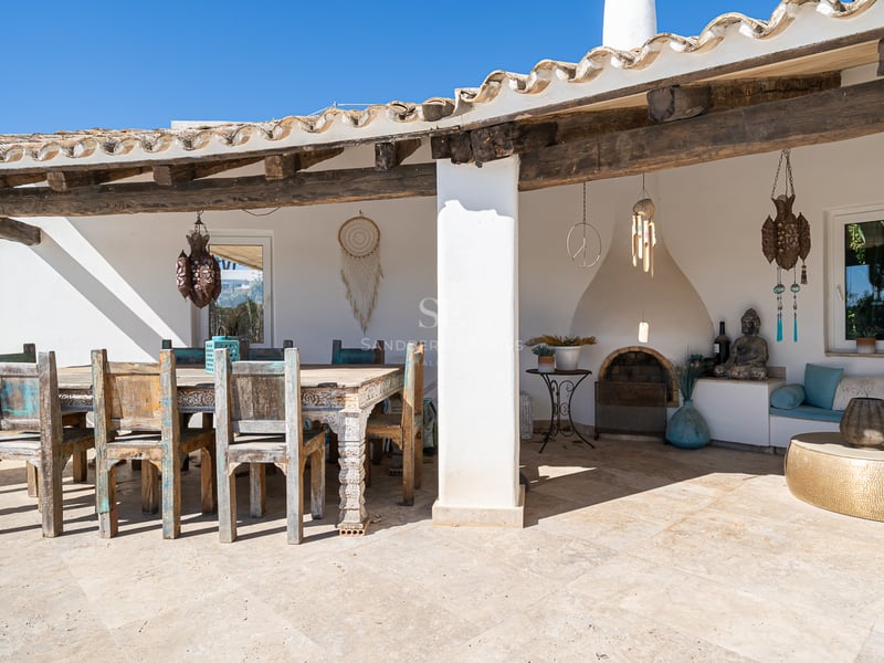 Terrasse couverte avec salle à manger en bois rustique, sol en pierre, cheminée intégrée et décoration méditerranéenne.