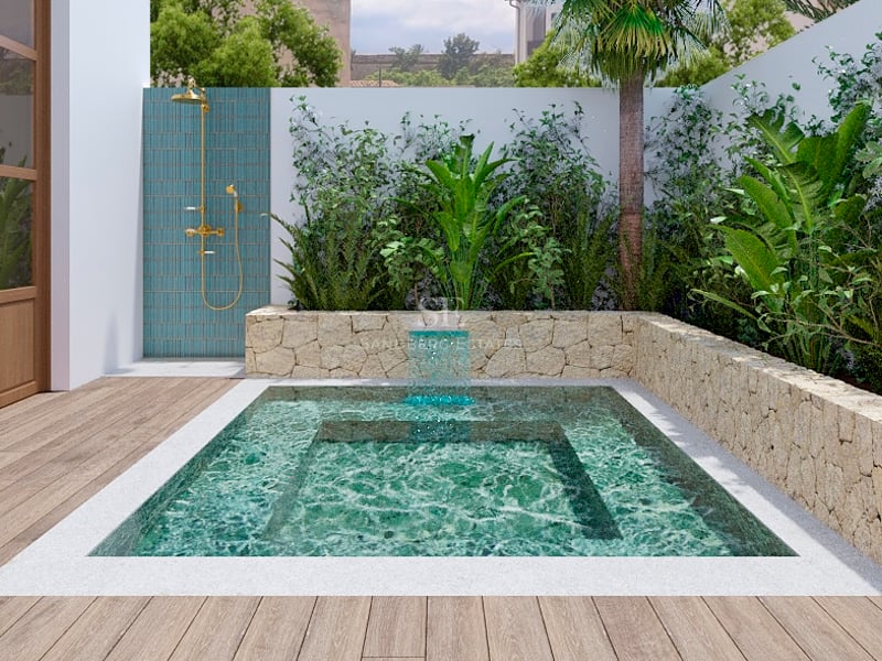Petite piscine turquoise avec cascade, entourée de murs en pierre et de plantes, à côté d'une douche extérieure en laiton.