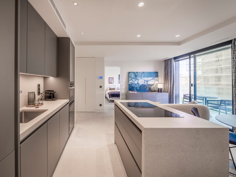 Cuisine contemporaine avec îlot en pierre, armoires anthracite et baies vitrées donnant sur une terrasse.
