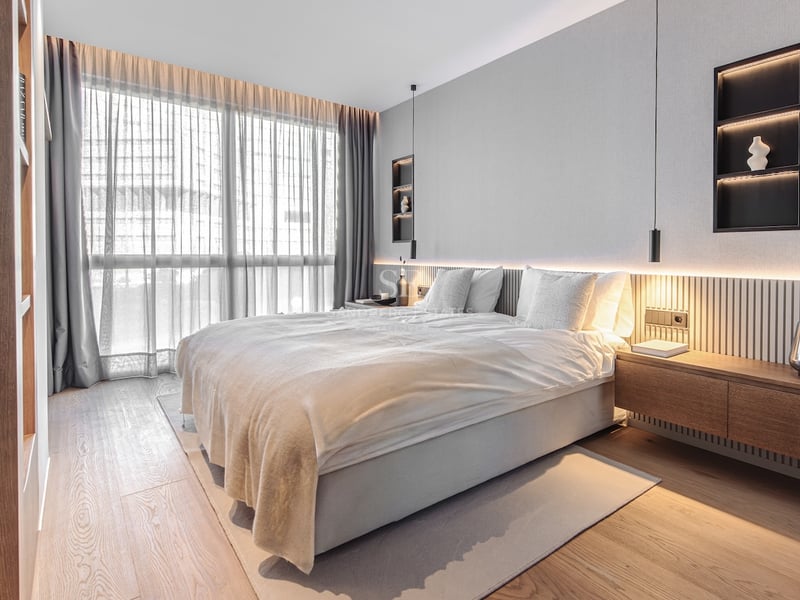 Modernes Schlafzimmer mit Eichenparkett, bodentiefen Fenstern und Holzkopfteil mit integrierter LED-Beleuchtung.