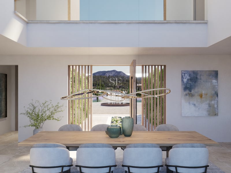 Salle à manger moderne avec table en chêne, luminaire design et vue panoramique sur les montagnes via une porte pivotante.