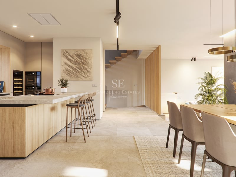 Vue d'une cuisine contemporaine ouverte avec menuiserie en bois clair, sol en pierre et îlot de petit-déjeuner.