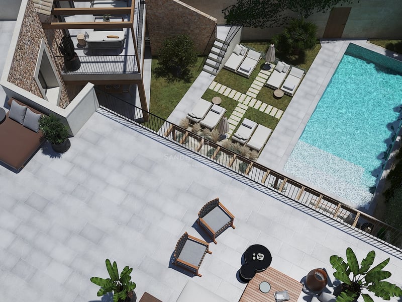 Vista aérea de una villa moderna con piscina turquesa, muros de piedra natural y amplias zonas de descanso exteriores.