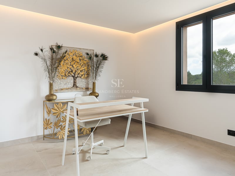 Un espace bureau moderne avec un bureau blanc, des œuvres d'art dorées et un éclairage LED indirect.