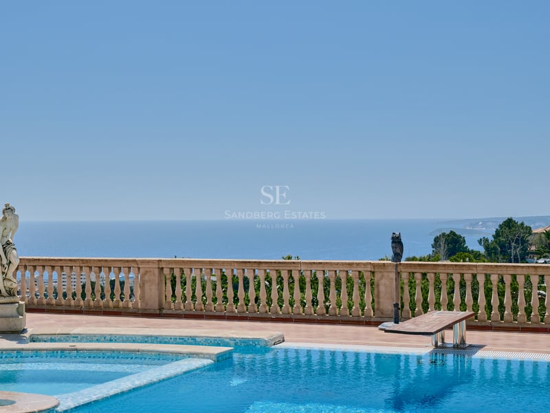 Grande piscine extérieure avec balustrade en pierre classique et statue dominant la mer Méditerranée.