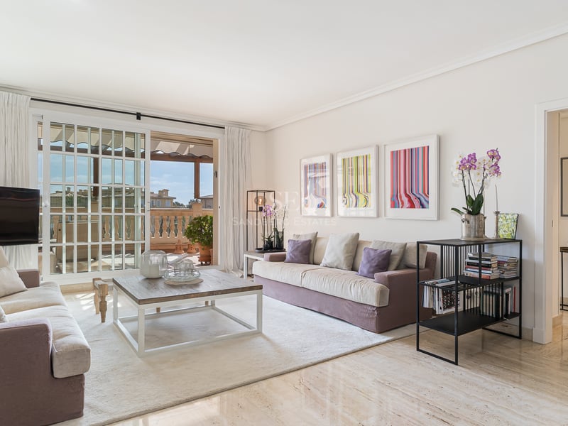 Salon lumineux avec sol en marbre, canapés mauves et grandes baies vitrées ouvrant sur une terrasse méditerranéenne.
