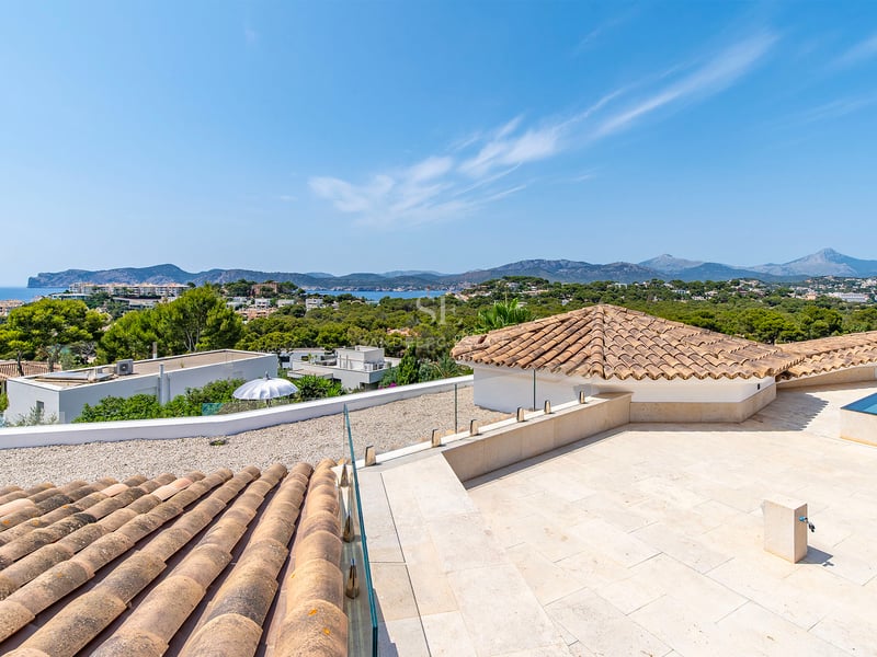 Extérieur d'une villa moderne avec piscine, grandes fenêtres et design minimaliste. Jardin luxuriant et ciel bleu.