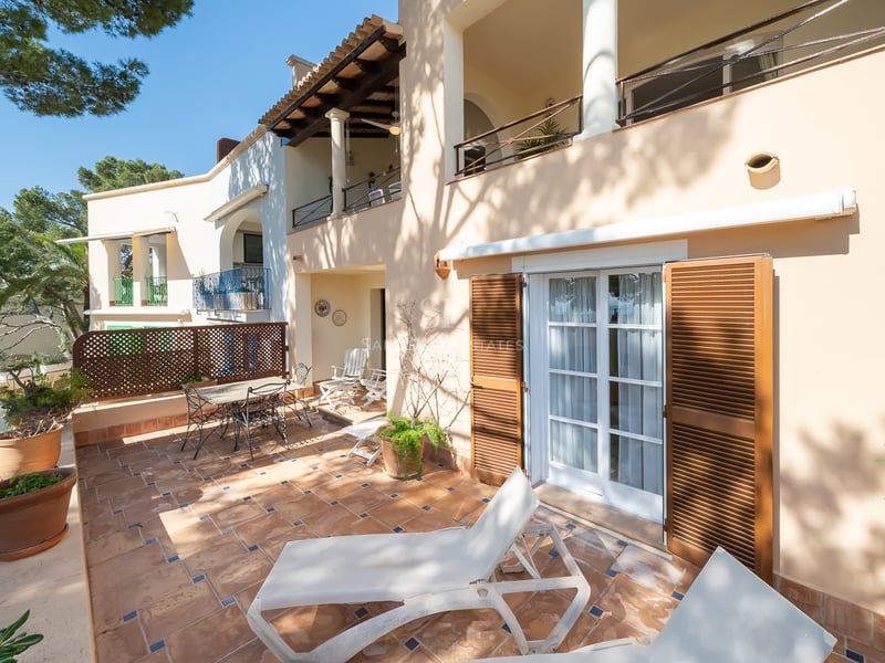 Terrasse ensoleillée avec carrelage en terre cuite, chaises longues blanches et coin repas extérieur.