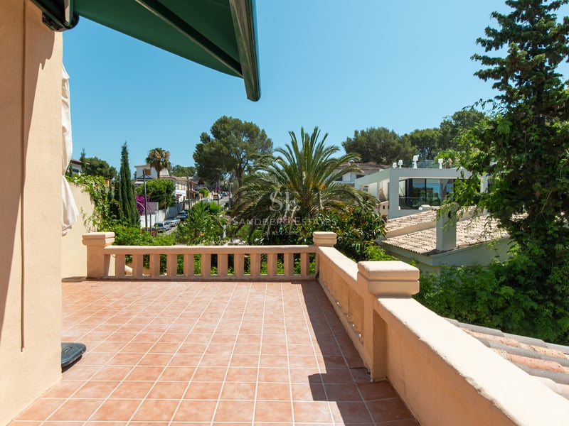 Terrasse baignée de soleil avec carrelage en terre cuite et balustrade classique surplombant la verdure méditerranéenne.