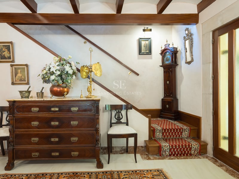 Entrée traditionnelle avec commode en bois sombre, horloge de parquet et escalier avec tapis rouge.