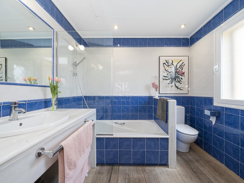 Salle de bain contemporaine avec carrelage bleu cobalt et blanc, plan de toilette en marbre et baignoire avec paroi en verre.