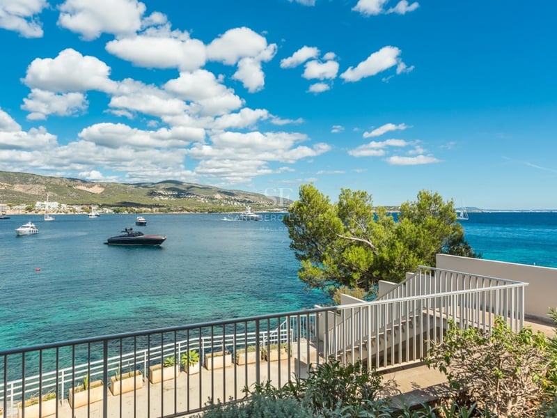Salon lumineux avec grandes baies vitrées, parquet clair et vue panoramique sur la mer. Mobilier moderne et élégant.