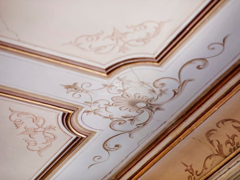 Molduras de techo ornamentadas con filigrana floral pintada a mano en crema y oro.