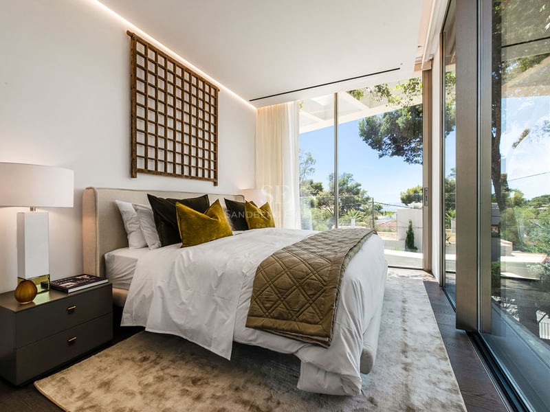 Chambre moderne avec grandes baies vitrées, coussins en velours et décoration murale en treillis de bois.
