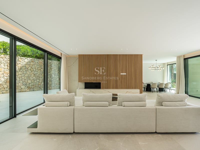 Grand canapé modulaire blanc dans un salon lumineux avec baies vitrées et boiseries murales.