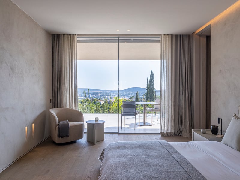 Chambre moderne avec parquet en chêne ouvrant sur une terrasse privée offrant une vue panoramique sur les collines.