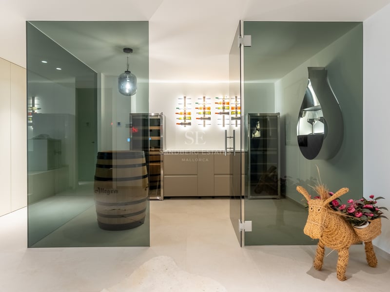 Cave à vin contemporaine avec portes vitrées, casiers rétroéclairés, armoires climatisées et tonneau en bois.