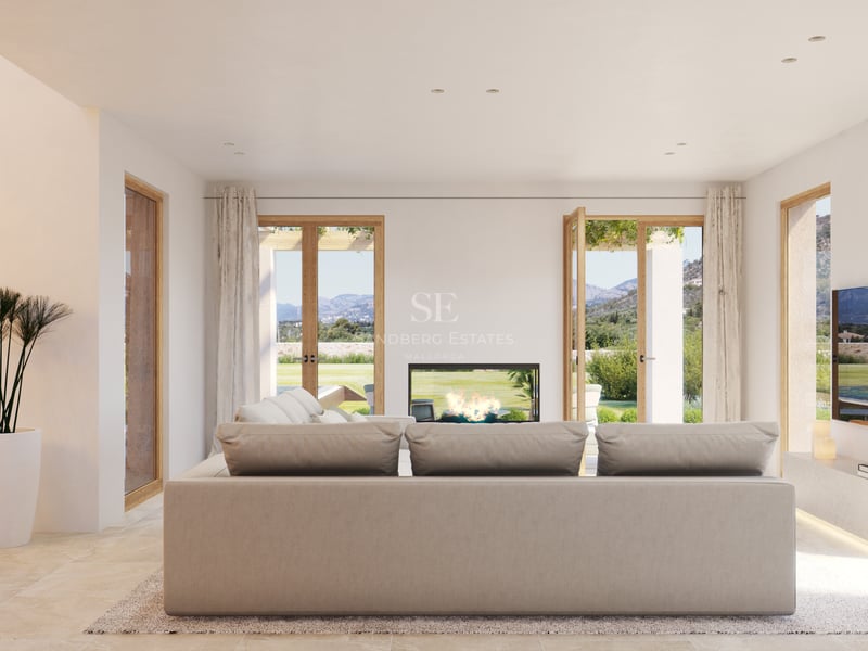 Salon moderne lumineux avec grandes portes en chêne, canapé beige, sol en pierre et cheminée face au jardin.