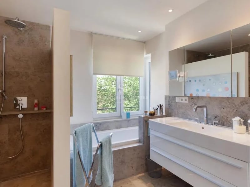 Salle de bains contemporaine avec douche à l'italienne en pierre, grand meuble vasque et baignoire sous fenêtre.