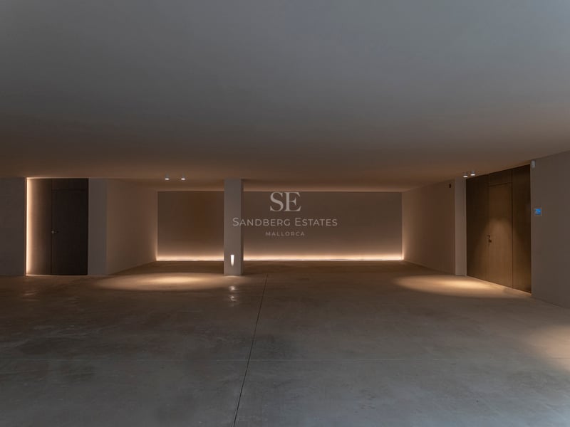 Vue large d'un garage souterrain minimaliste avec sol en béton poli et éclairage LED indirect chaleureux.
