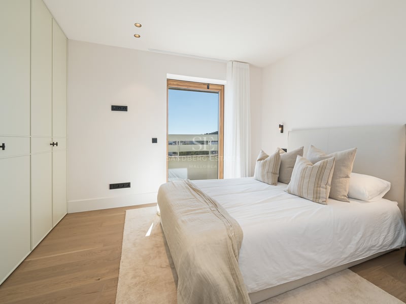 Chambre lumineuse avec parquet en chêne, placards blancs toute hauteur et grande fenêtre.