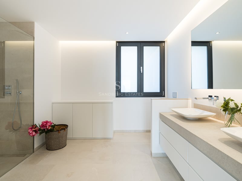 Salle de bain principale moderne avec douche à l'italienne, double vasque sur comptoir en pierre et miroir rétroéclairé.