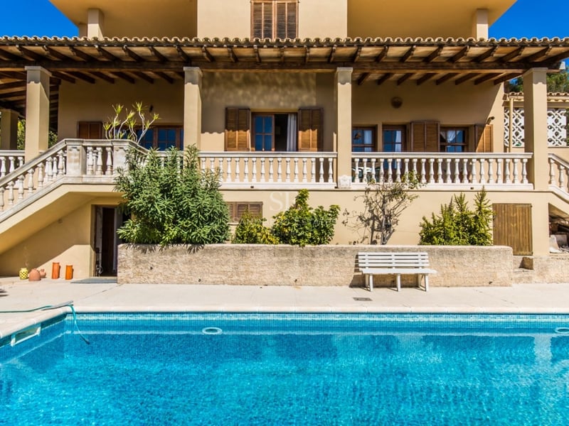 Villa de style méditerranéen avec une grande piscine bleue et une terrasse avec balustrade en pierre.
