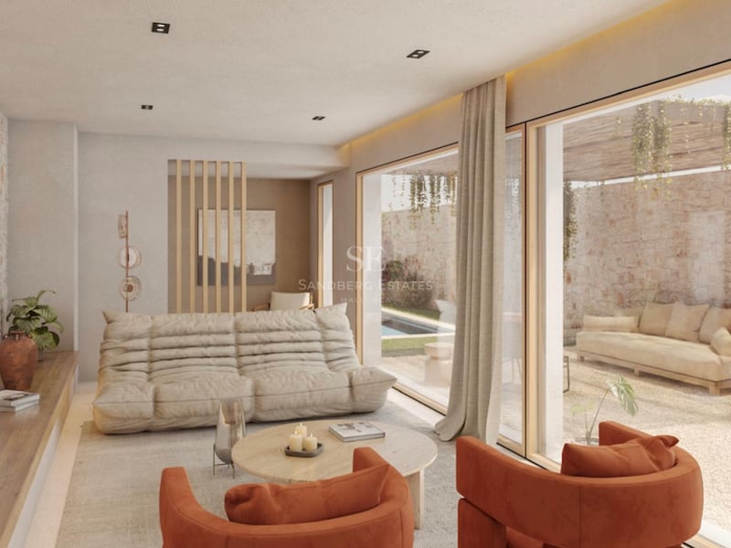 Salon moderne avec canapé beige, fauteuils en velours orange et grandes baies vitrées ouvrant sur une terrasse en pierre.