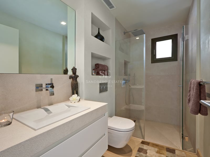 Salle de bain moderne avec vasque en pierre, WC suspendu et douche à l'italienne vitrée.