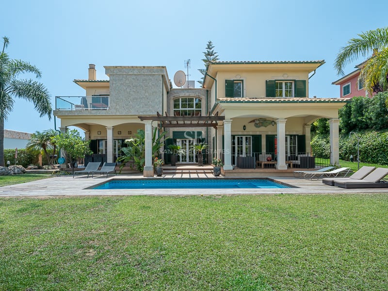 Villa méditerranéenne jaune avec piscine, volets verts, grand jardin et terrasses couvertes par temps clair.