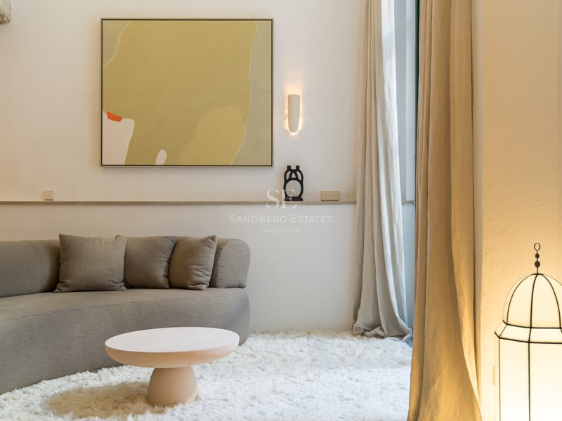 Salon minimaliste avec canapé incurvé gris, tapis shaggy blanc et arches en pierre naturelle.