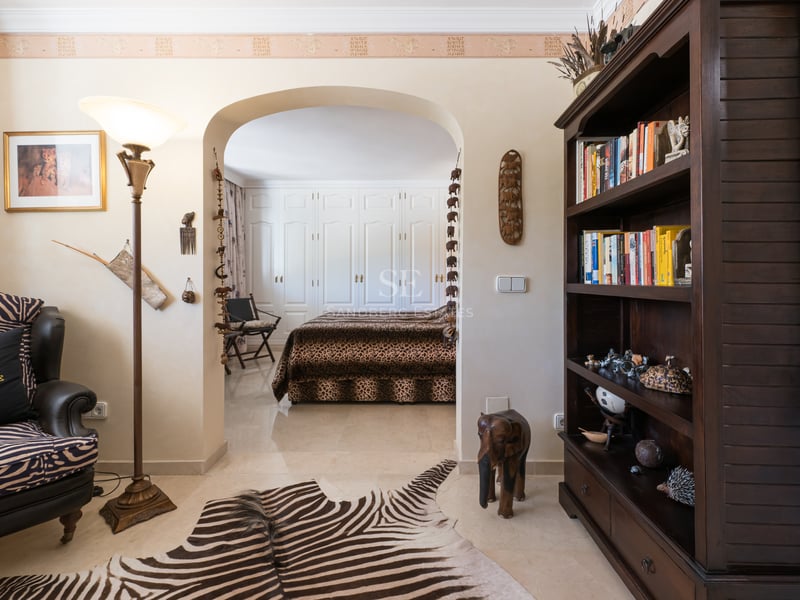 Salon à thème africain avec tapis en peau de zèbre menant à une chambre avec édredon léopard.