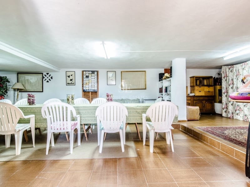 Grande table à manger avec chaises blanches dans une pièce carrelée au décor traditionnel.