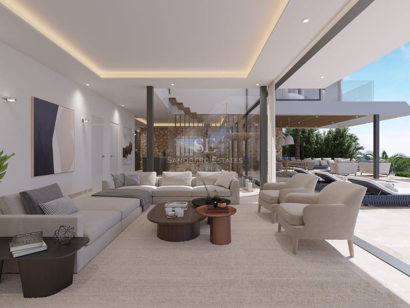 Salon de luxe avec canapés crème et baies vitrées s'ouvrant sur une terrasse ensoleillée et piscine.