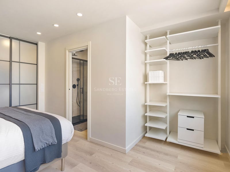 Chambre contemporaine lumineuse avec système de dressing blanc, parquet clair et aperçu de la salle de bain attenante.