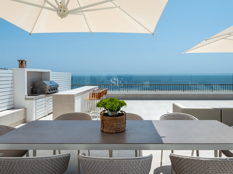 Toit-terrasse de luxe avec coin repas, cuisine d'été et garde-corps en verre surplombant la mer Méditerranée.