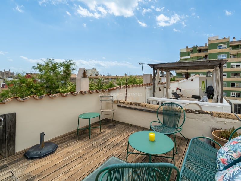 Terrasse de toit avec terrasse en bois, sièges turquoise et vue sur la cathédrale de Palma.
