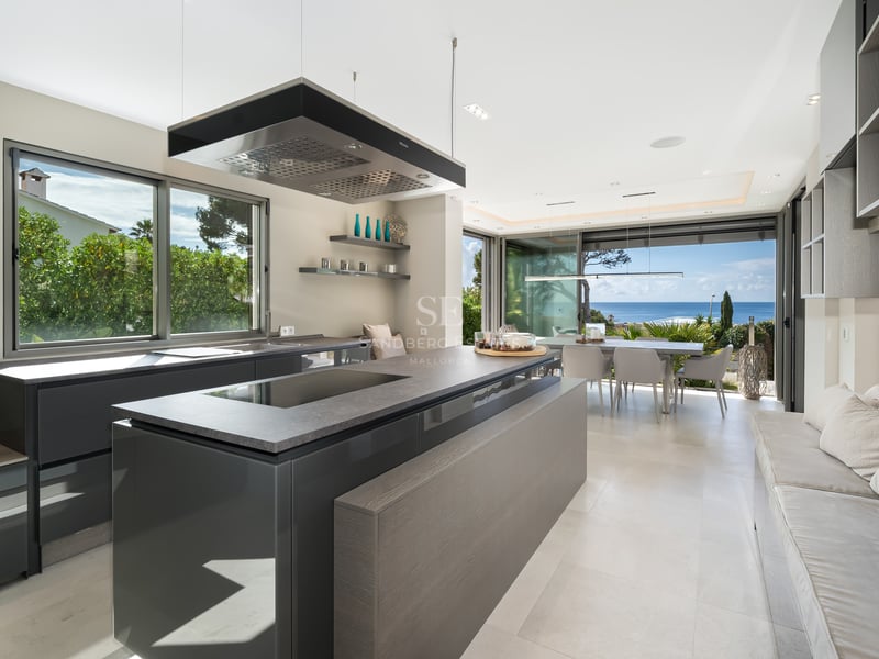 Cuisine moderne avec îlot gris, hotte design et grandes baies vitrées donnant sur la Méditerranée.