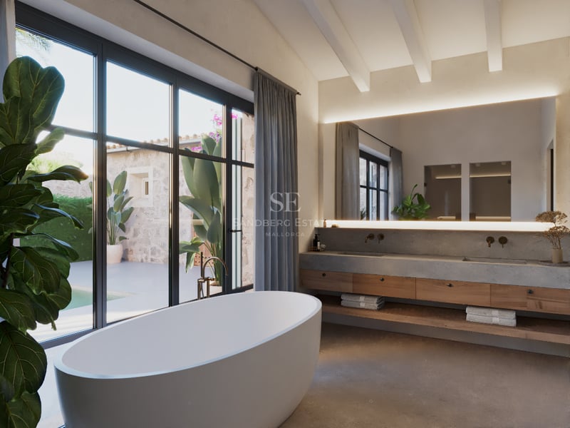 Une salle de bain principale minimaliste avec baignoire îlot, meuble en bois et béton, et grandes fenêtres sur cour.