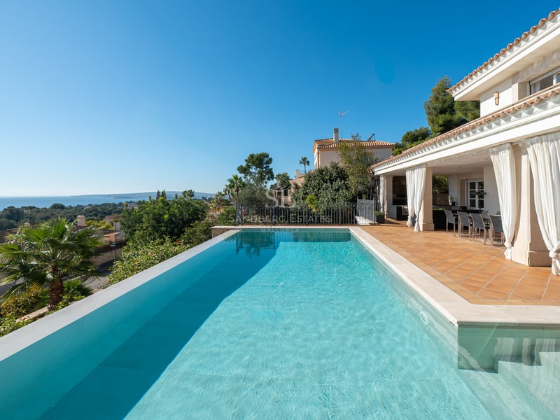 Piscine à débordement sur une terrasse en terre cuite surplombant la mer Méditerranée et le littoral.